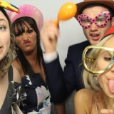 four guests at wedding taking pictures in a photo booth hired by Animation Events at a wedding in Wimbledon